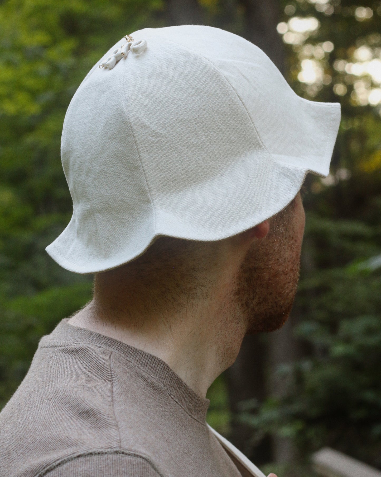 Person wearing a white bucket hat with a blurred natural background