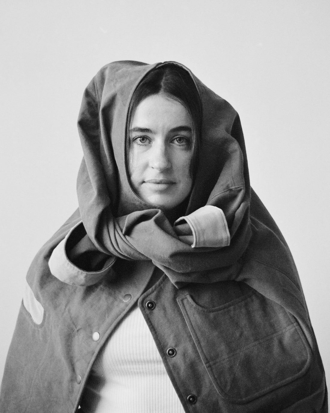 Person wearing a hooded coat against a plain background