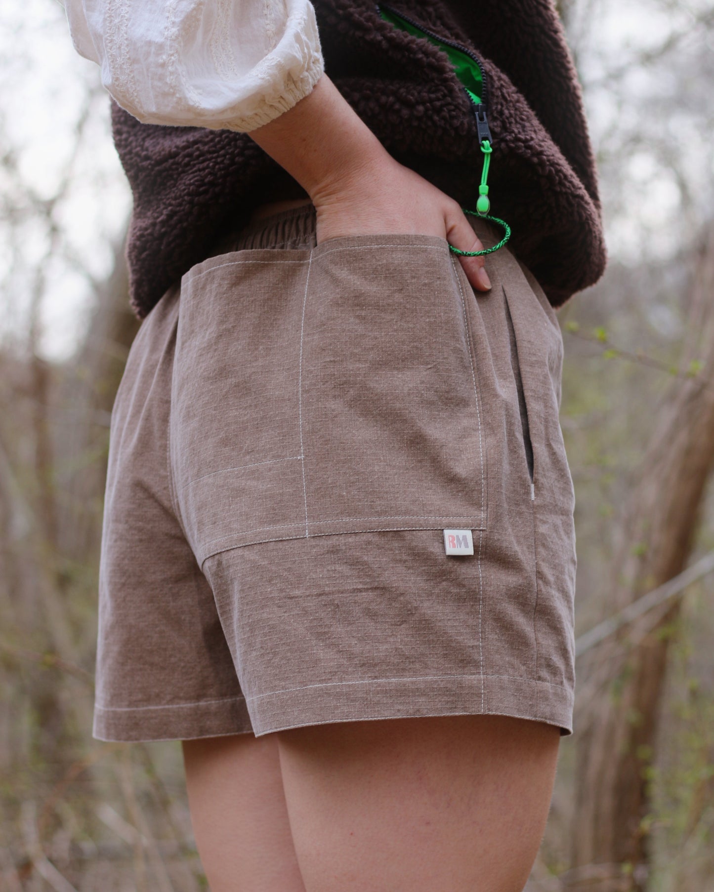 Women wearing brown shorts with hand in back pocket