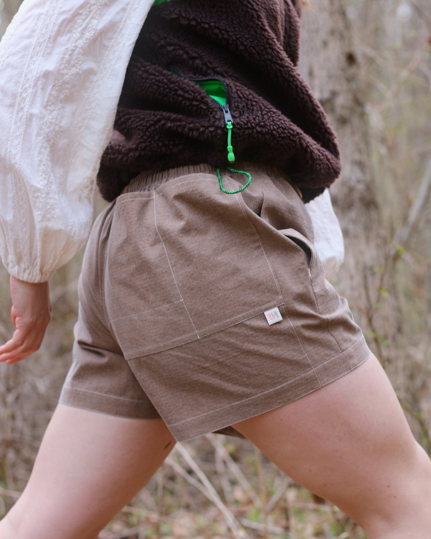 Women wearing brown shorts with woodsy background
