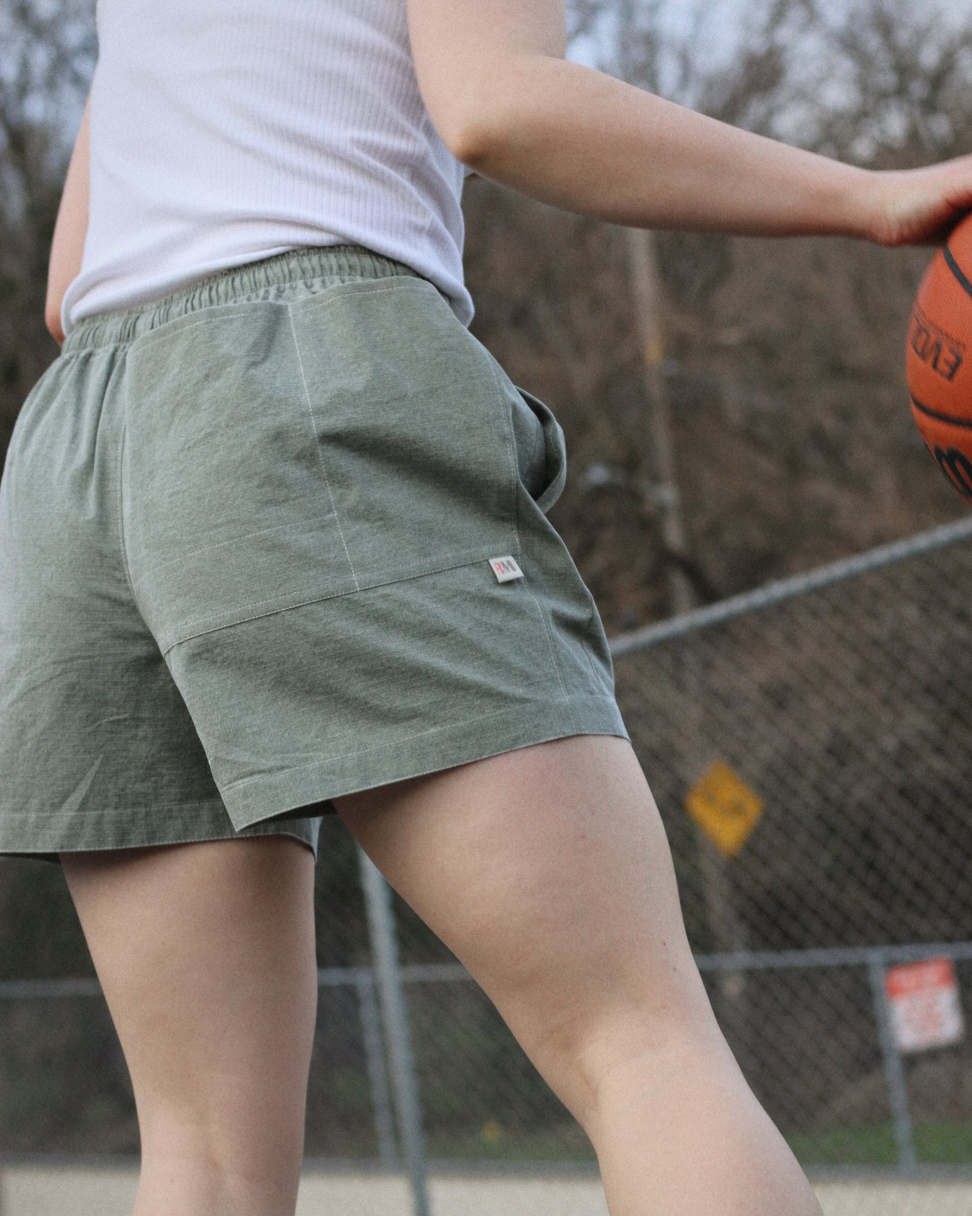 Women wearing greens shorts and dribbling a basketball