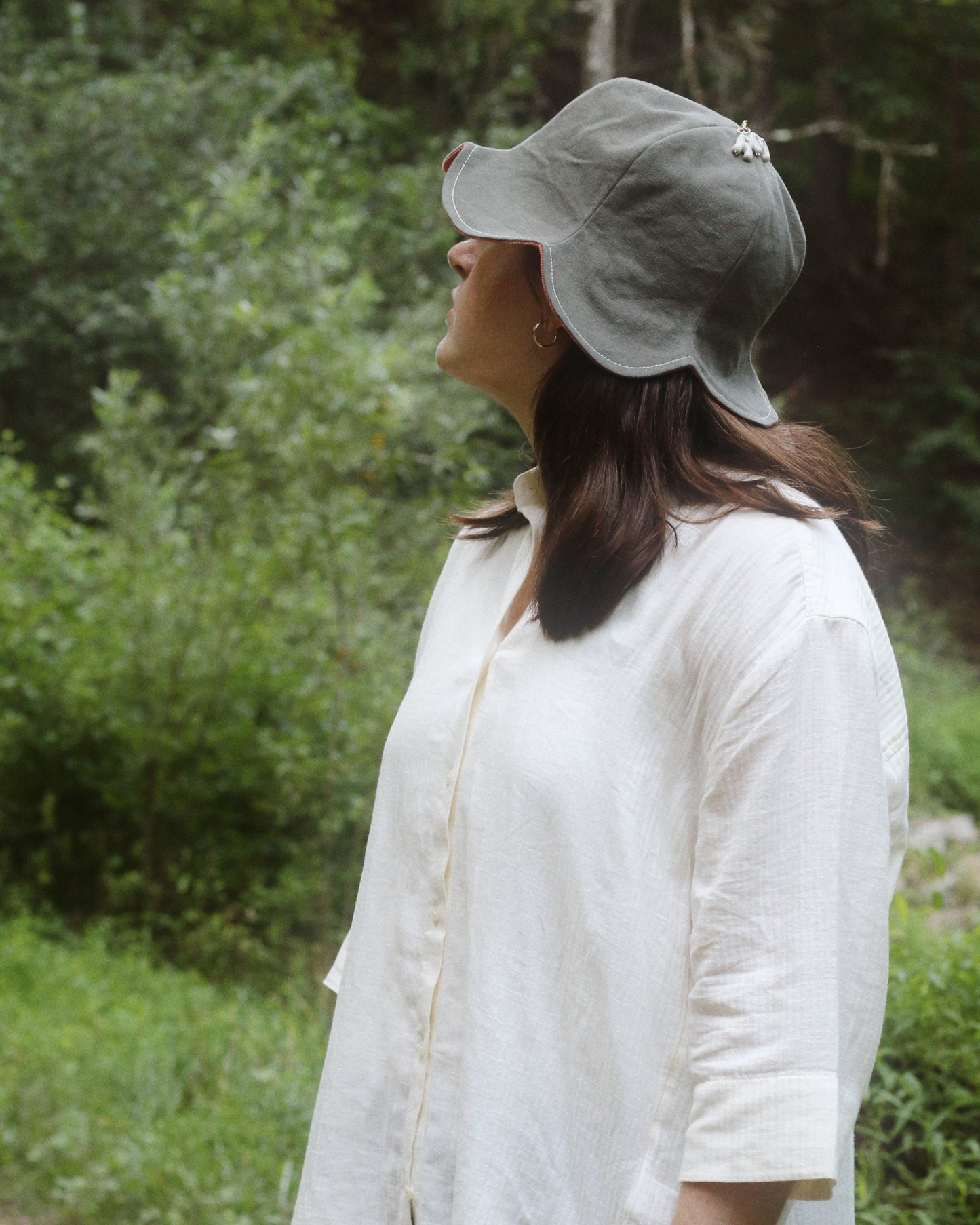 Woman wearing a gray cap and white shirt standing in a forest