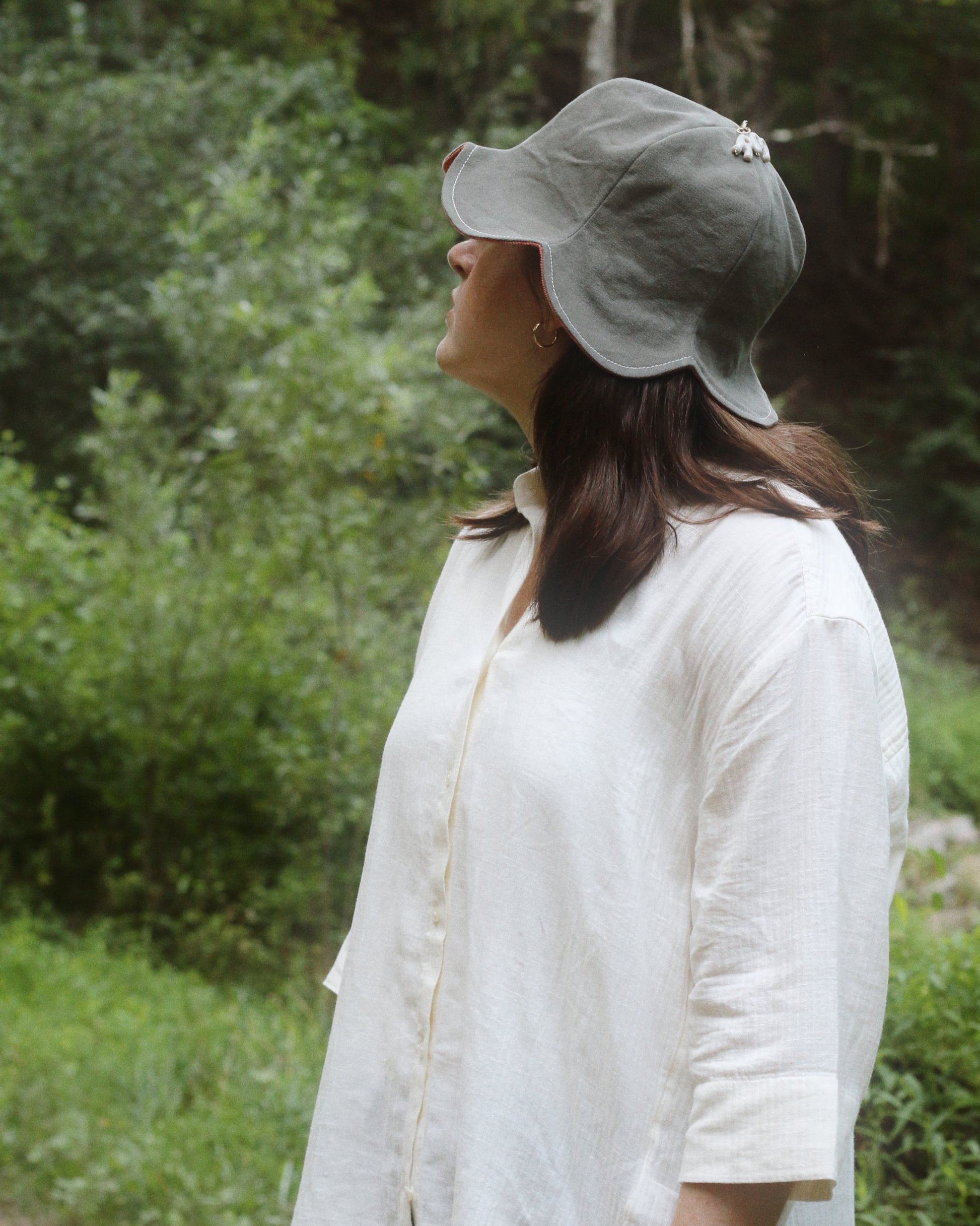 Woman wearing a gray cap and white shirt standing in a forest